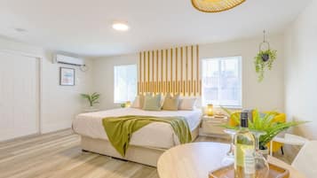 Relax in a serene space with a large bed, bedside table, and natural light pouring in through the window.