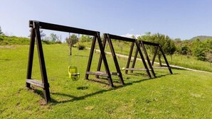 Eine Reihe von Holzschaukeln in einem grünen Feld unter blauem Himmel.