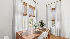 Ein Essbereich mit einem Holztisch, weißen Stühlen und einer Vase mit Blumen.