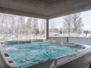 Un jacuzzi con vistas a árboles cubiertos de nieve.