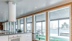 Eine moderne Küche mit einem Bosch-Ofen, großen Fenstern und Blick auf einen Garten.