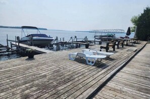 Une jetée en bois, avec des chaises longues et un bateau amarré à son extrémité.