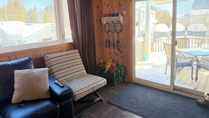 Een gezellige kamer met een bank, een kleine tafel en een schuifdeur naar een terras.