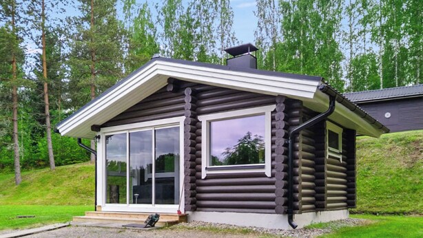 Hirsimökki, jossa on suuri liukuovi ja savupiippu.
