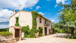 Un bâtiment doté d’une cour pavée de pierres, d’une porte en bois et d’un balcon.