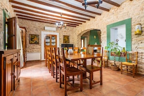 A rustic dining area with wooden furniture, stone walls, and a tiled floor.