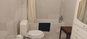 Un baño con inodoro, bañera y espejo.