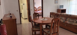Una habitación con una mesa de comedor, sillas, un sofá, un televisor y un extintor.