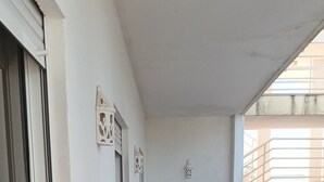 A corridor with a tiled floor, white walls, and a window with a metal railing. - Apartment 'T1 Em Alvor' with Sea View, Shared Pool and Shared Garden (Alvor)
