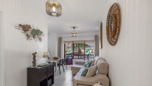 A living room with a sofa, a TV, a dining table, and a decorative wall piece.