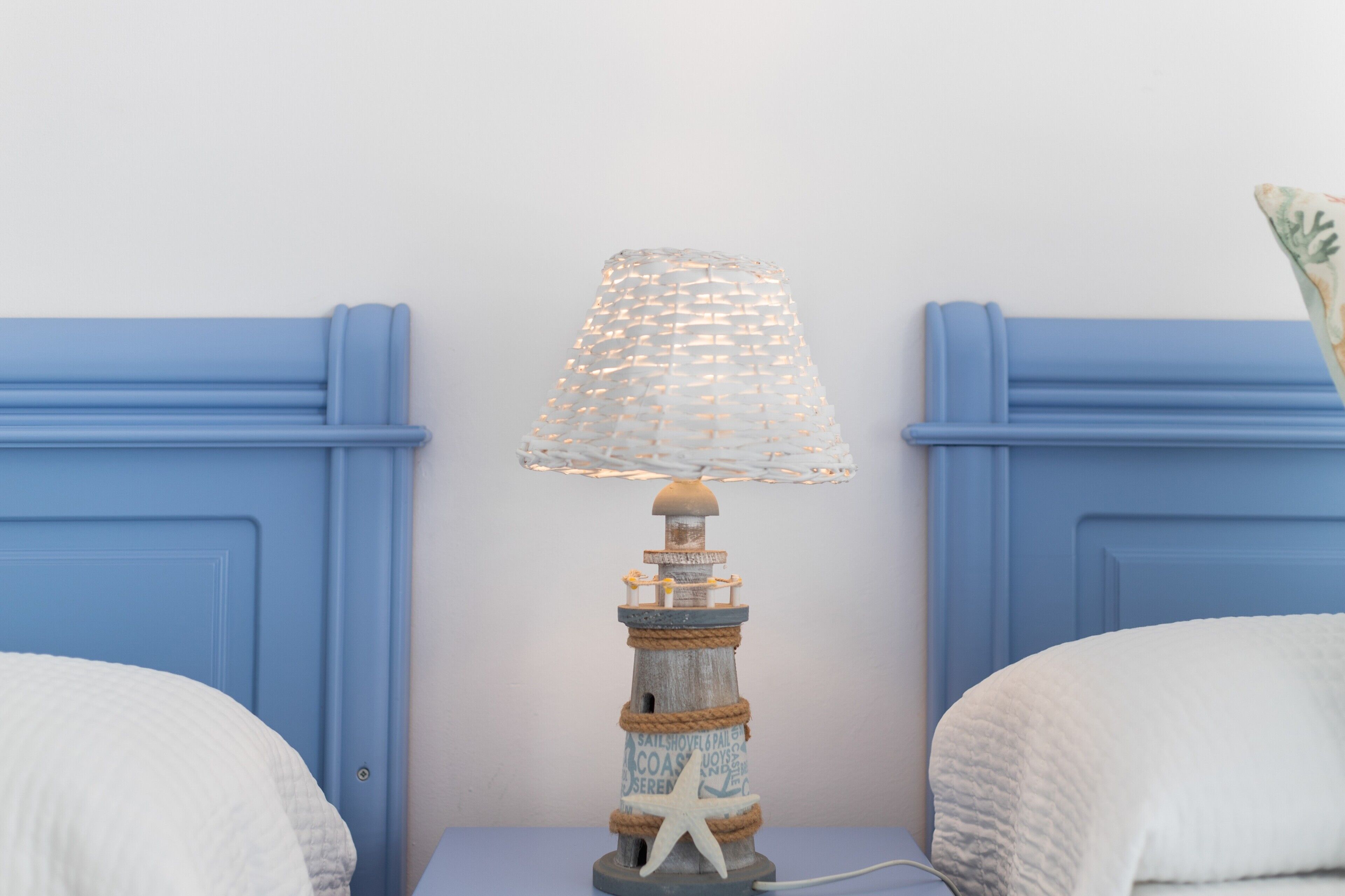 A bed with a blue headboard, a decorative lamp with a starfish base, and a white pillow.