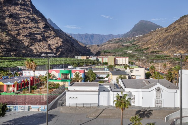 A mountainous landscape with buildings, including a white structure with a gate and a colorful building with a green roof.