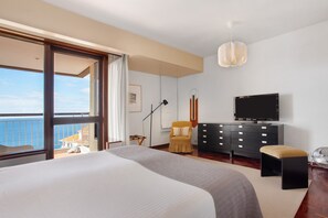 Een slaapkamer met een groot bed, een televisie, een kaptafel en een stoel.