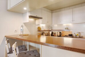 Een keuken met witte kastjes, een houten aanrecht en een ingebouwde kookplaat.
