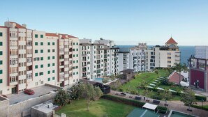 A residential building with multiple floors, balconies, and a view of the sea.