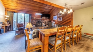 Ein gemütliches Blockhaus-Interieur mit einem Holzespeisesaal, Stühlen, einem Kamin und einem Fernseher.