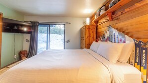Ein Schlafzimmer mit einem großen Bett, einem Holzkopfteil und einem Skiständer mit Skiern.