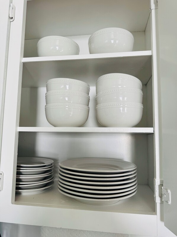 A cabinet with white shelves containing white bowls and stacked plates. - 3-bedroom house. Everything you need in one spot. quiet and cozy home. (Temple)