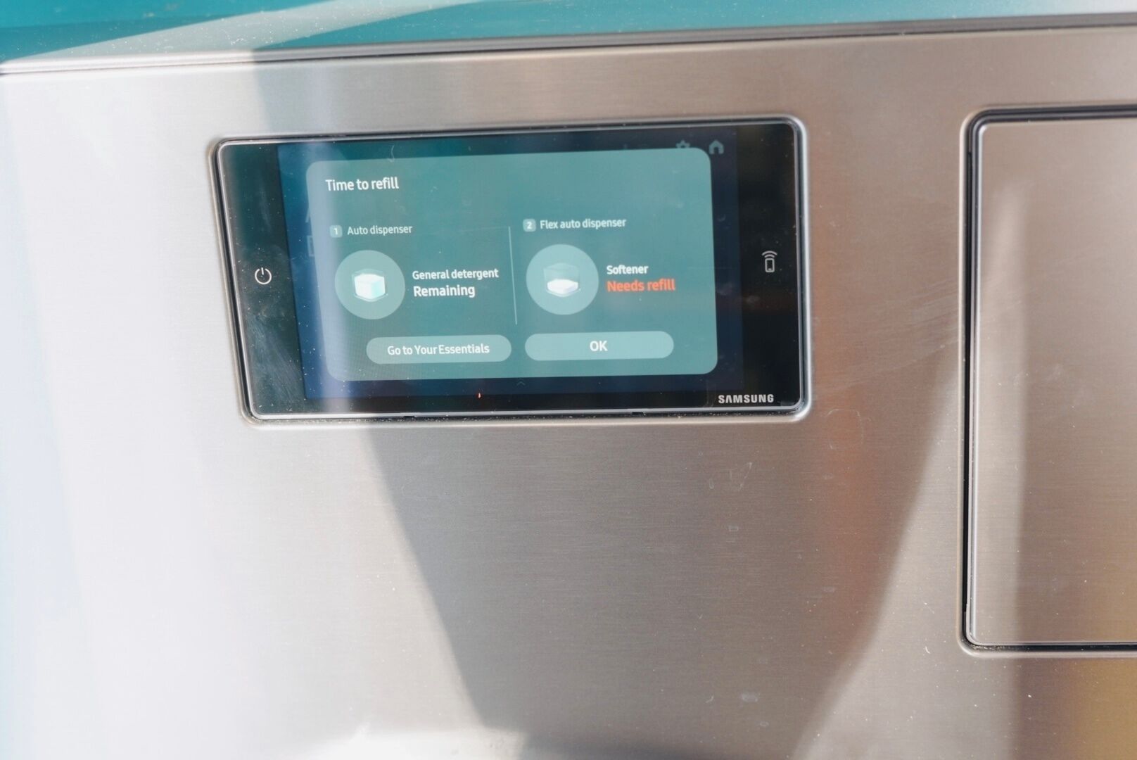 Ein Samsung-Gerät, dessen Bildschirm eine Erinnerung zum Nachfüllen für automatische und flexible Automaten anzeigt, einschließlich Waschmittel und Weichspüler.