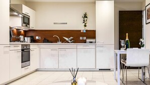 A modern kitchen with white cabinets, a built-in oven, and a dining area with a white table and chairs. - City Centre | Cathedral Quarter | Walk Everywhere - Pass the Keys (Belfast)