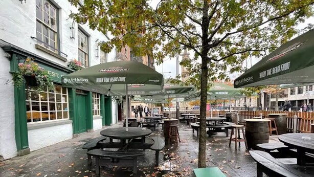 An outdoor seating area with tables and umbrellas, surrounded by buildings. - City Centre | Cathedral Quarter | Walk Everywhere - Pass the Keys (Belfast)