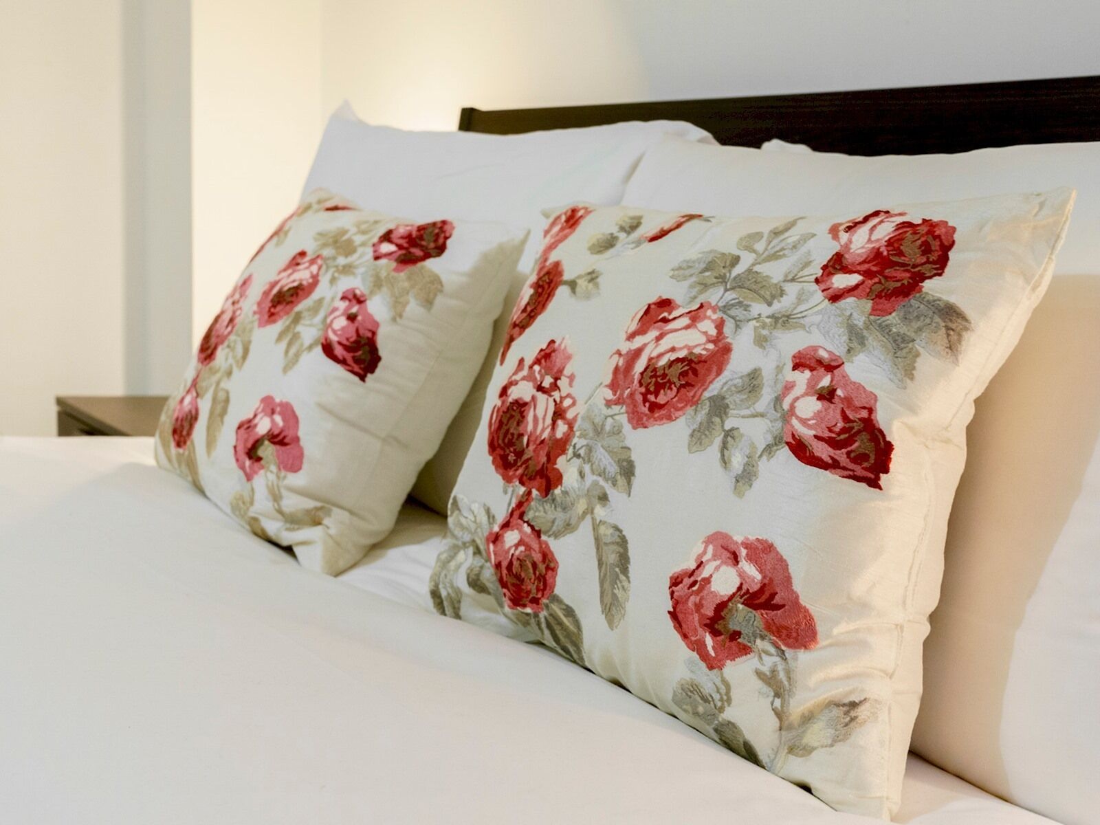 A bed with two pillows featuring a floral pattern.