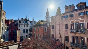 A row of historic buildings with red-tiled roofs and balconies, under a clear sky.