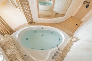 Ein Spa-Raum mit einer großen Badewanne, einem Spiegel und einem Holzboden.