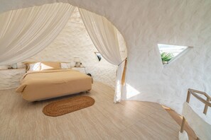 Ein Schlafzimmer mit einem Bett, Vorhängen, einem kleinen Fenster und einem hölzernen Stuhl.