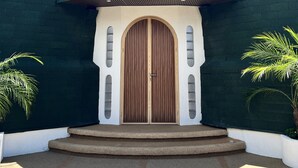 A modern building with a large wooden door, a curved roof, and a white wall with windows. - The Dome Villa Canggu (Canggu)