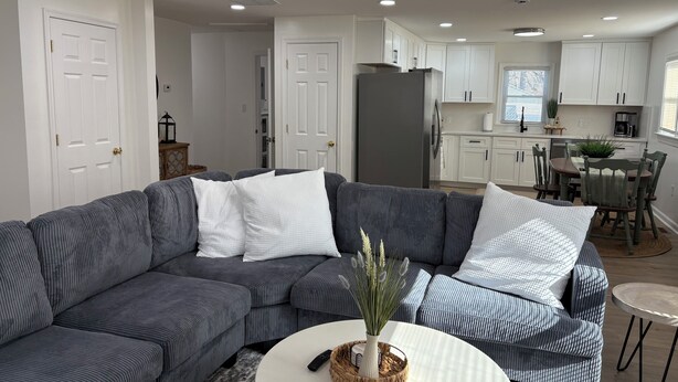 A modern living room with a grey striped sofa, a small white table, and a kitchen area in the background.
