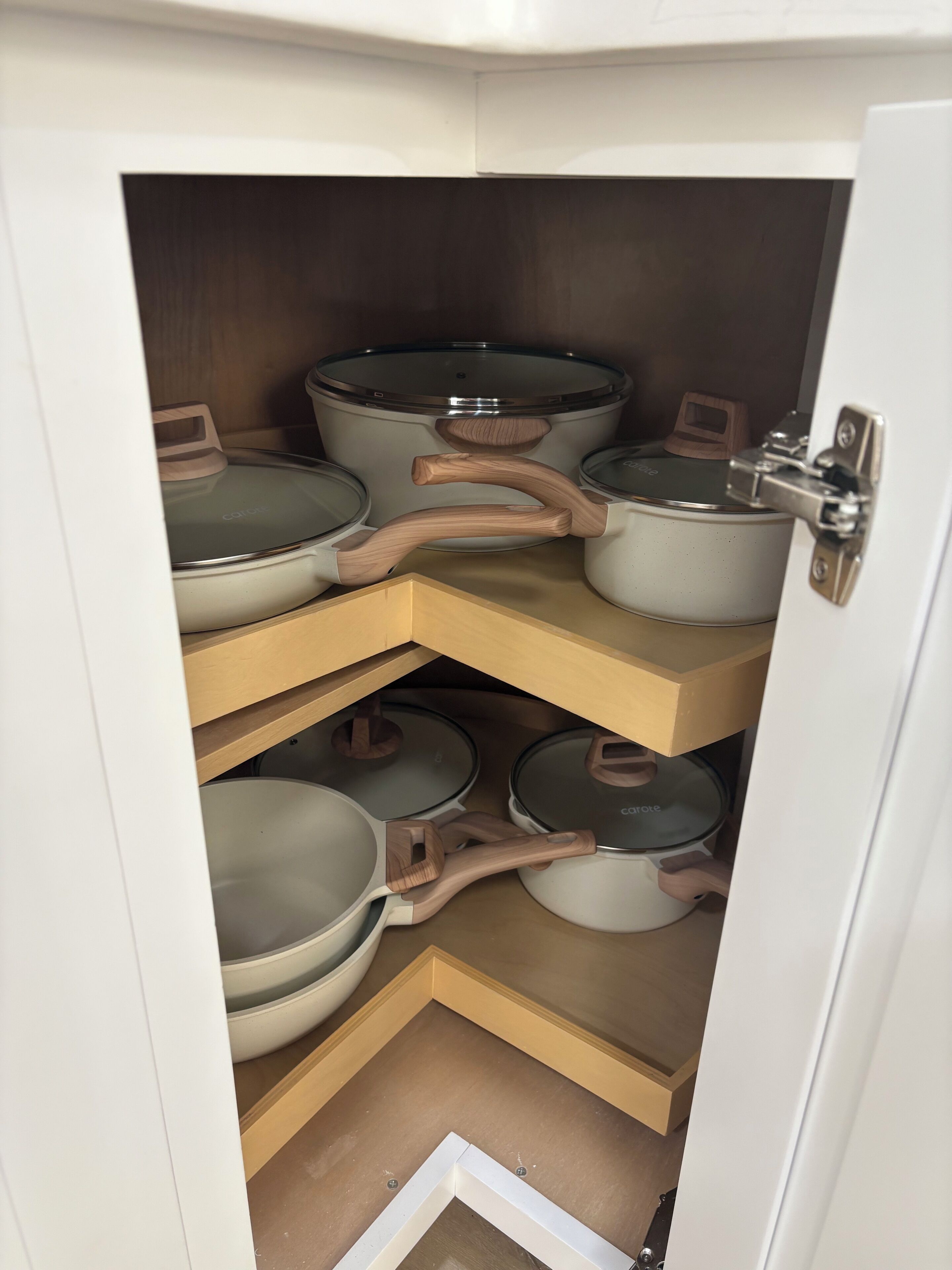 Un armario de cocina con varias ollas y sartenes.