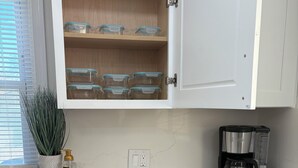 A kitchen with white cabinets, a coffee maker, a dishwasher, and a plant on the counter.