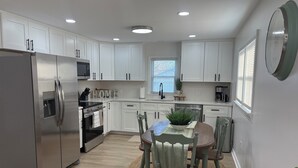 A modern kitchen with white cabinets, stainless steel appliances, and a dining area with a round table and chairs.