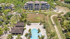 A resort with a central swimming pool, multiple-story buildings, and lush greenery. - Renovated 2-bedroom condo with WiFi, AC inside Bahía Beach Resort (Río Grande)