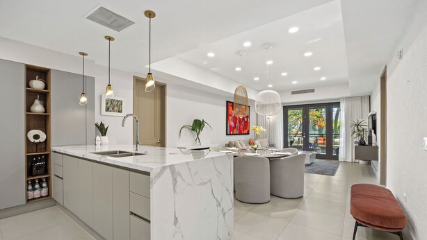 A modern kitchen with a marble island, pendant lighting, and a dining area with a grey sofa and ottoman. - Renovated 2-bedroom condo with WiFi, AC inside Bahía Beach Resort (Río Grande)