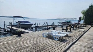 A wooden pier with lounge chairs and a boat docked at the end.