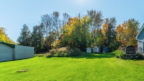 A well-maintained lawn with a small shed and a house in the background.