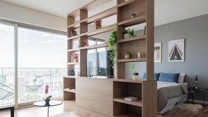 A modern living room with a large TV, wooden shelving, a round table, and a balcony with a view of the city. - MOT Azopardo 700 (Buenos Aires)