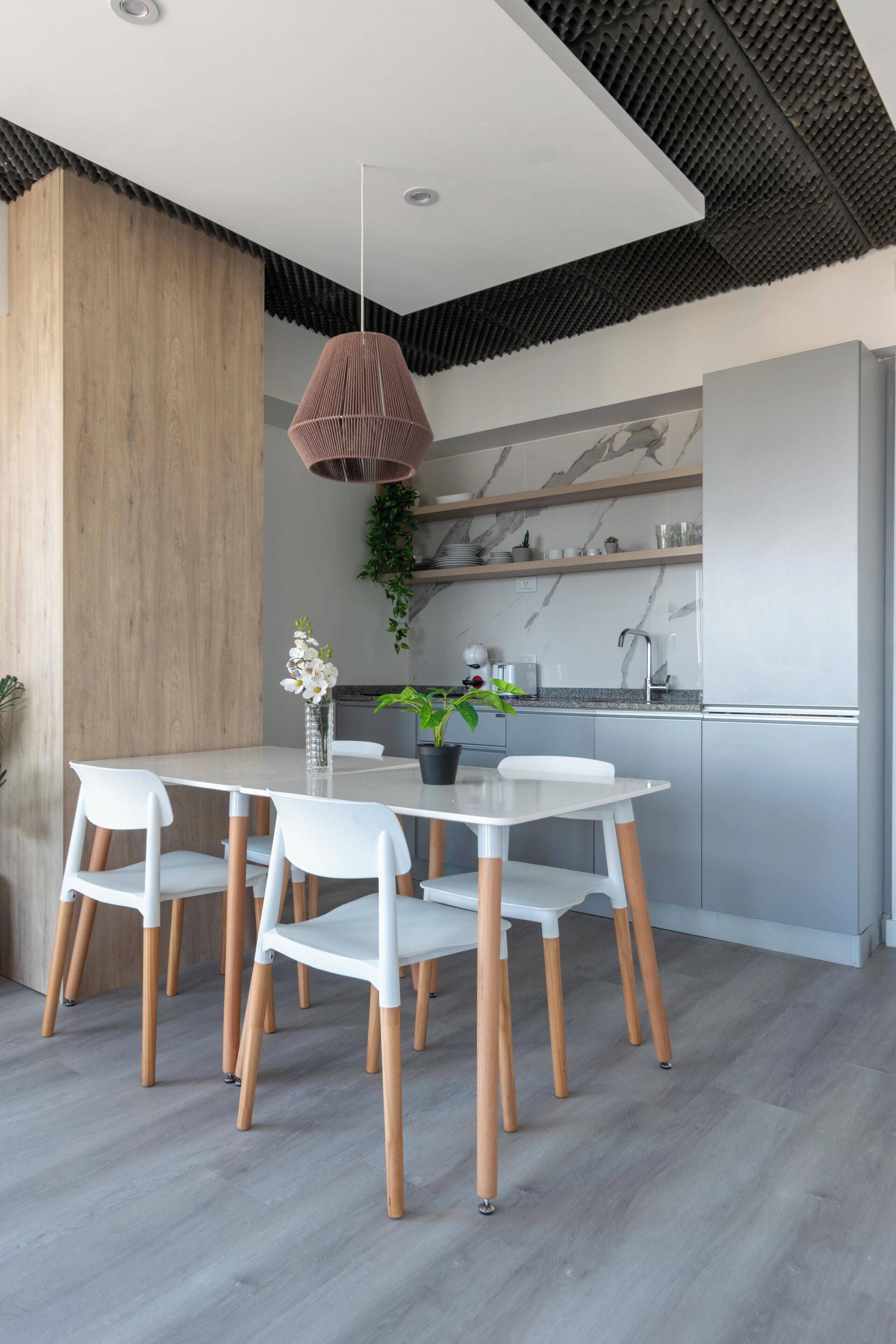 A modern kitchen with a white countertop, grey cabinets, and a hanging pendant light.