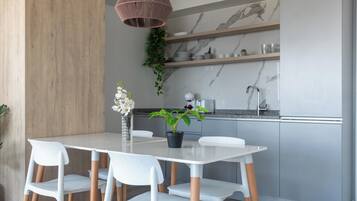 A modern kitchen with a white countertop, grey cabinets, and a hanging pendant light.