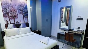Una habitación de hotel moderna con una cama grande, un escritorio con una silla, un espejo y un televisor de pared.