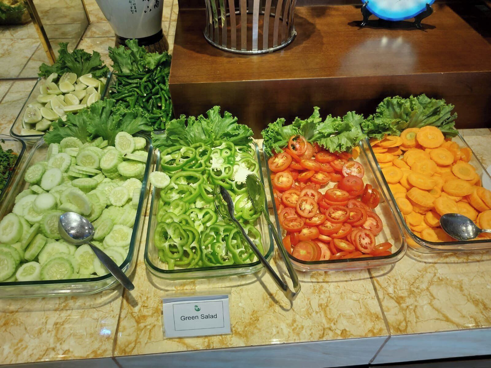 A salad bar with various fresh vegetables like cucumbers, green peppers, tomatoes, and carrots.
