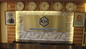 Un mostrador de recepción con un cartel que dice "KHAIRUL INTERNATIONAL HOTEL" y relojes mostrando diferentes husos horarios.