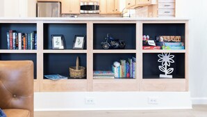 Un salon moderne avec une bibliothèque intégrée, un fauteuil en cuir et un espace cuisine situé à l’étage supérieur.