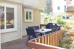Een terras met een tafel, stoelen, een barbecue en een houten omheining.