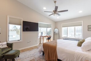 Een slaapkamer met een bed, een bureau, een stoel, een televisie en een plafondventilator.