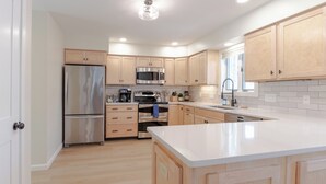 Une cuisine moderne avec des meubles en bois, des appareils en acier inoxydable et un plan de travail blanc.