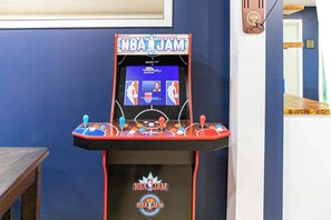 A basketball arcade game with the NBA logo, a wooden table, and a blue wall. - Happy Valley Retreat ~ Epic Game Room ~ 130" TV Wall ~ 10 min to Campus/Downtown (State College)