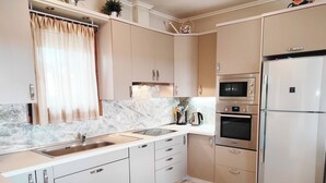 A modern kitchen with a marble backsplash, stainless steel appliances, and light-colored cabinetry. - Villa Traditional Estate Heated Pool (Nea Propontida)
